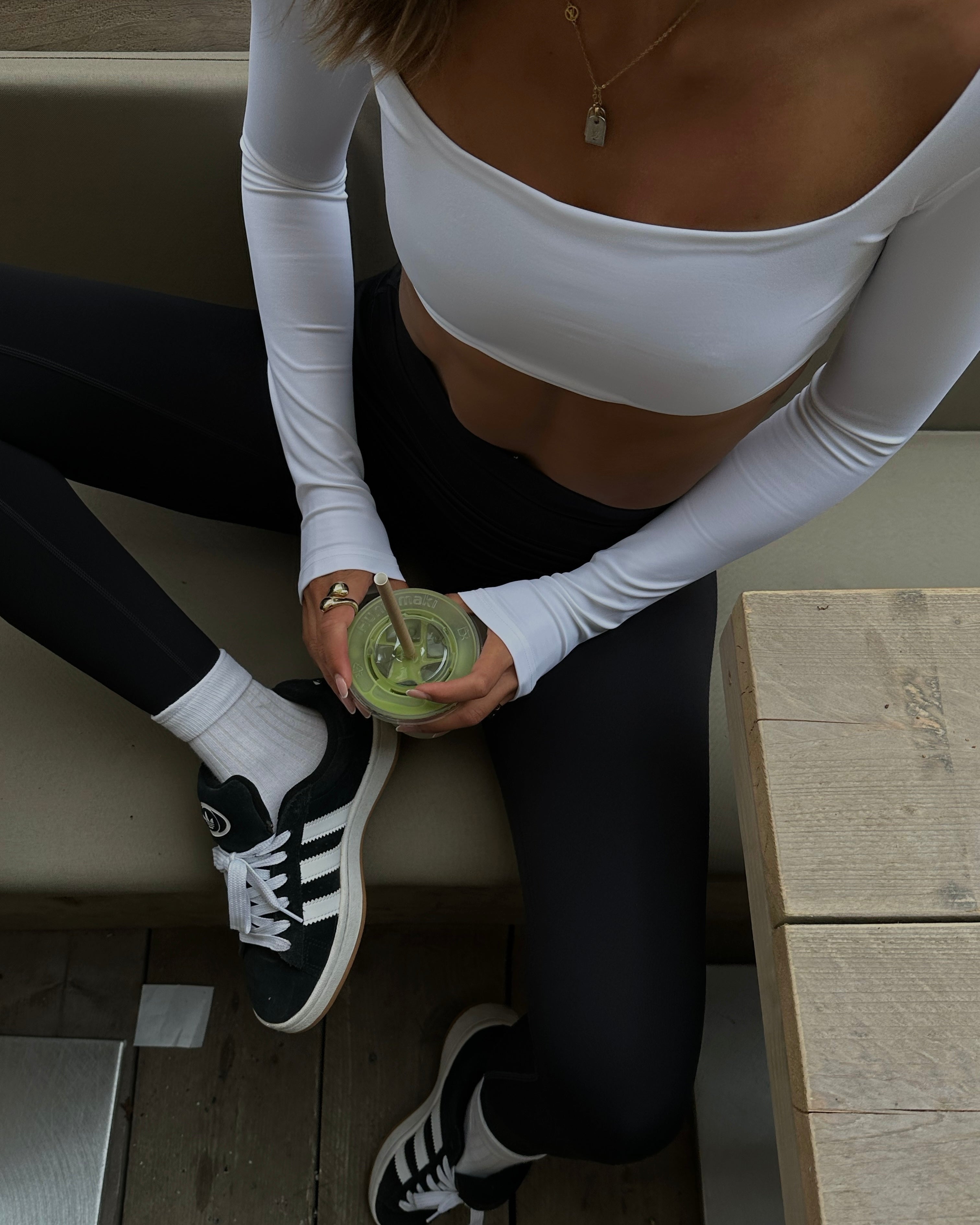 Frau trägt weißes Cropped Longsleeve und schwarze Cross Over Shorts von shop-samo.com