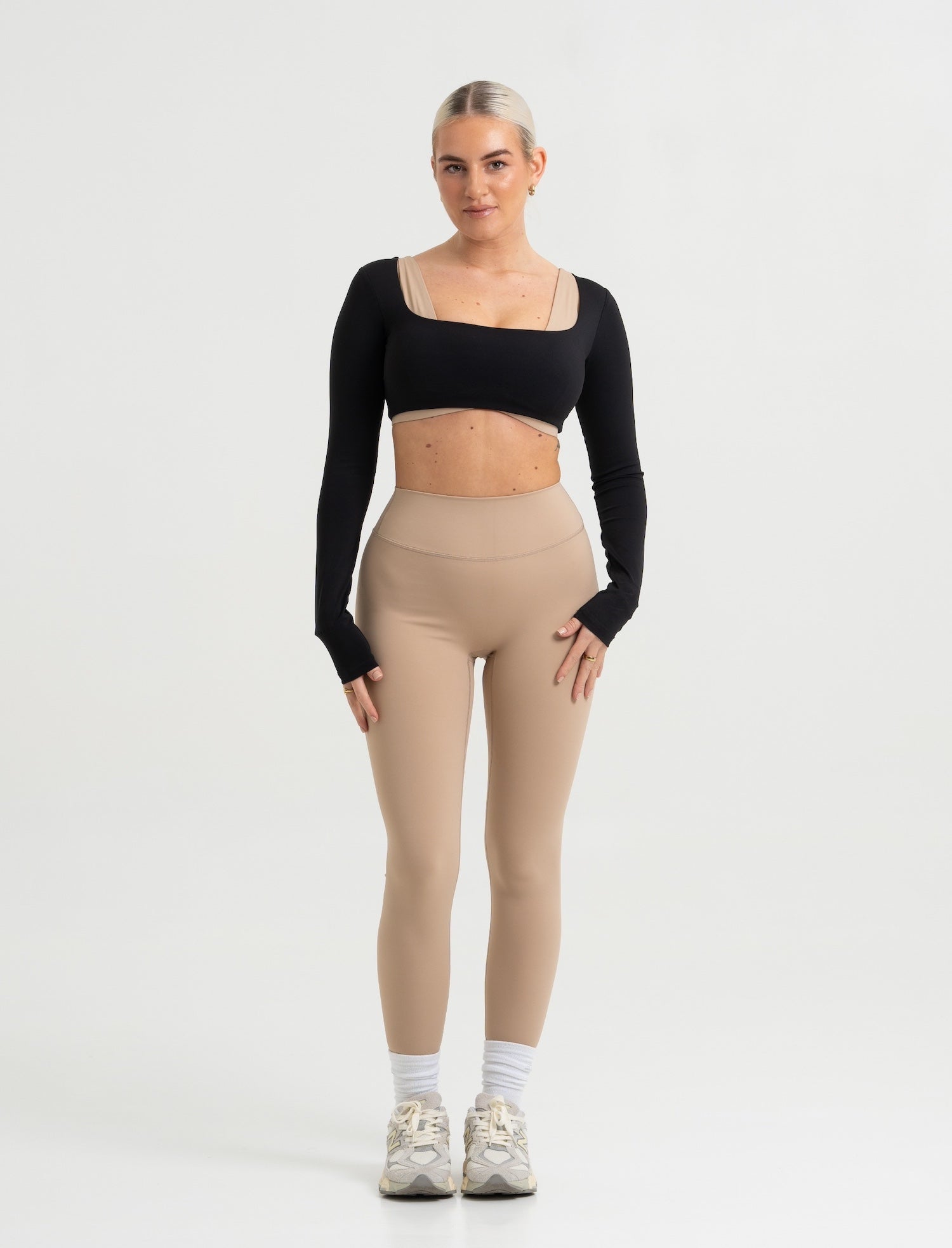 Frau trägt Seamless Pilates Leggings in Sand mit schwarzem Cropped Longsleeve von shop-samo.com
