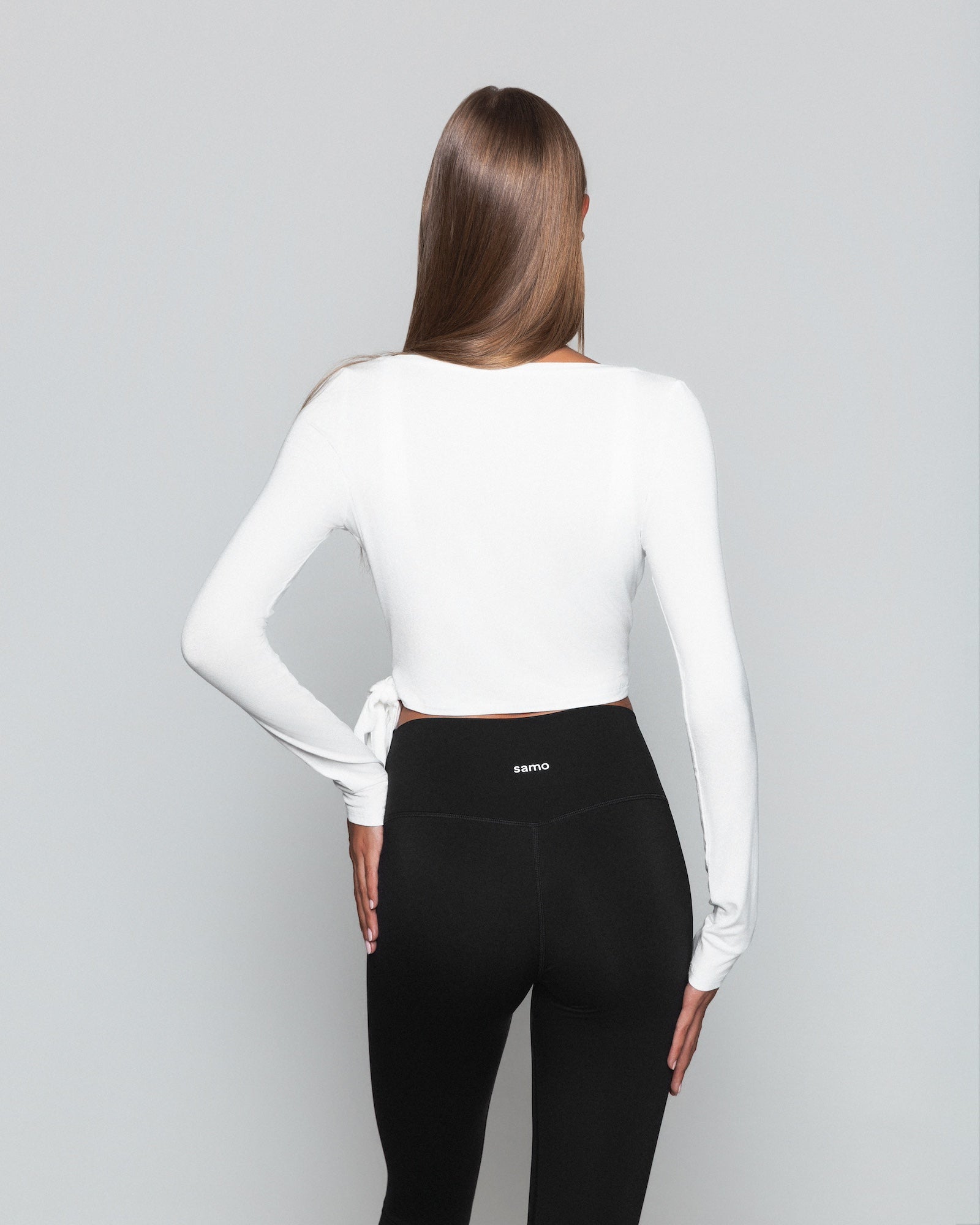 Frau trägt weisses Pilates Wickeloberteil und schwarze seamless leggings von shop-samo.com